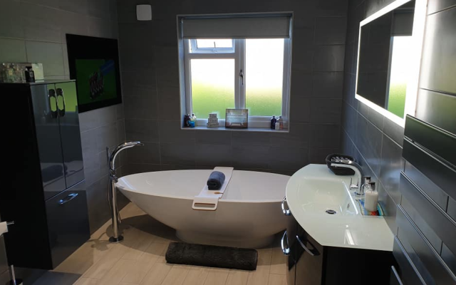 Sleek freestanding bath with grey walls and black floating vanity unit