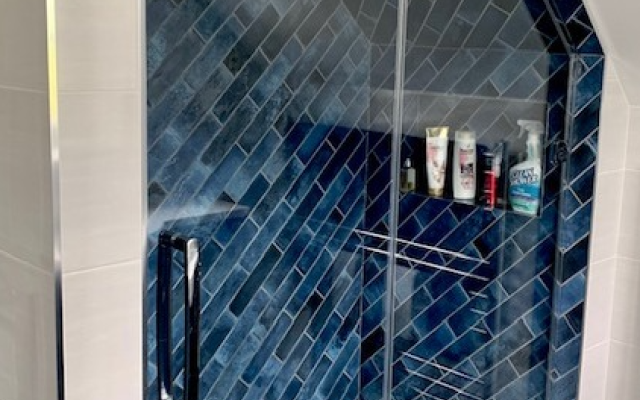 Shower enclosure with blue gloss tiles in a roof space